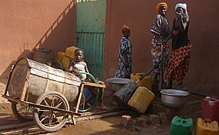 ménagères et porteurs d'eau font la queue à un point d'eau à pompe manuelle dans les quartiers non lotis de Ouagadougou