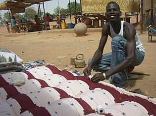 un jeune ouagalais confectionnant un matelas rembourré de coton représente le type même de travail informel