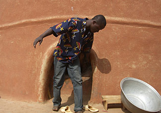 jeune kasséna du village de Tiébélé devant l'une des cases dites "en huit", véritable joyaux d'architecture et de décoration.